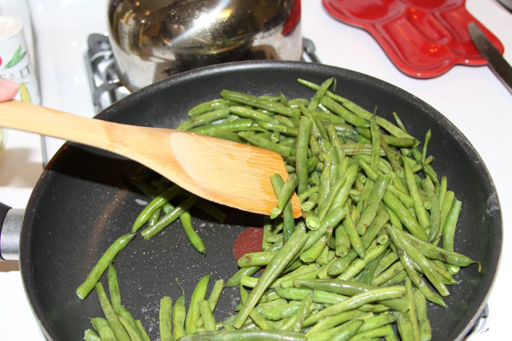 green beans being sautéed in a black frypan