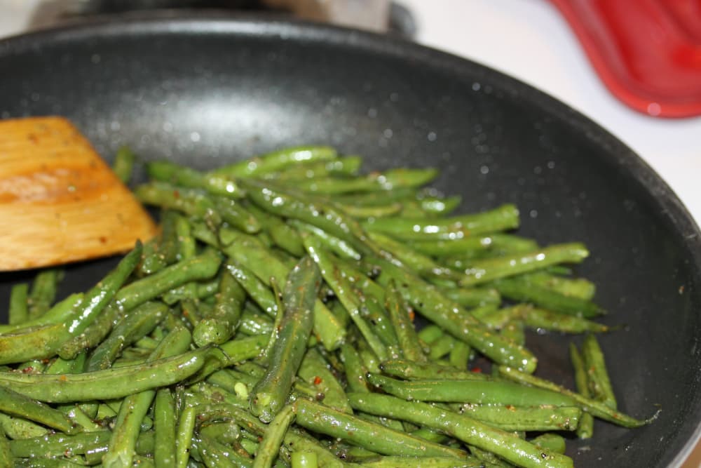 Sautéed seasoned green beans in a black frypan