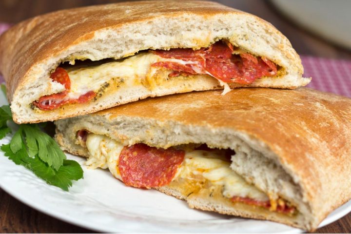 Pepperoni stromboli cut in half on a white plate.