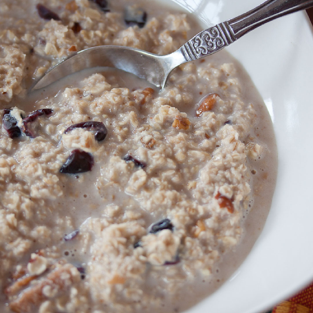 Oatmeal with raisins and nuts in a white bowl with spoon