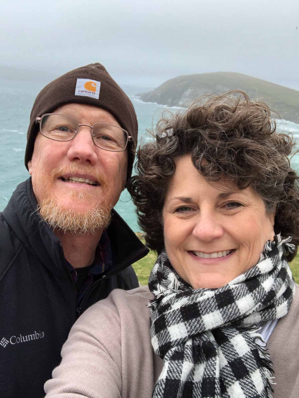 Man and woman in winter clothing facing camera with atlantic ocean and peninsula in background