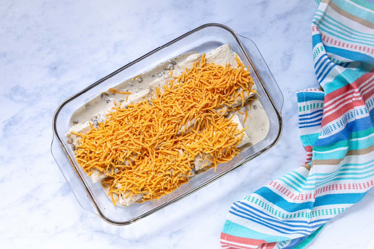 Frozen burritos covered in green chili and mushroom sauce and topped with shredded cheddar cheese.