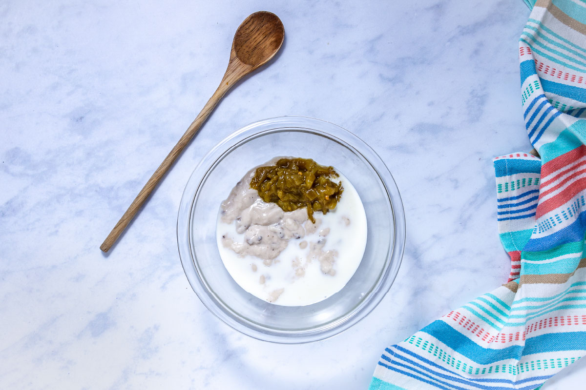 Sauce for frozen burrito casserole in a bowl: condensed cream of mushroom soup, milk, and green chilies.