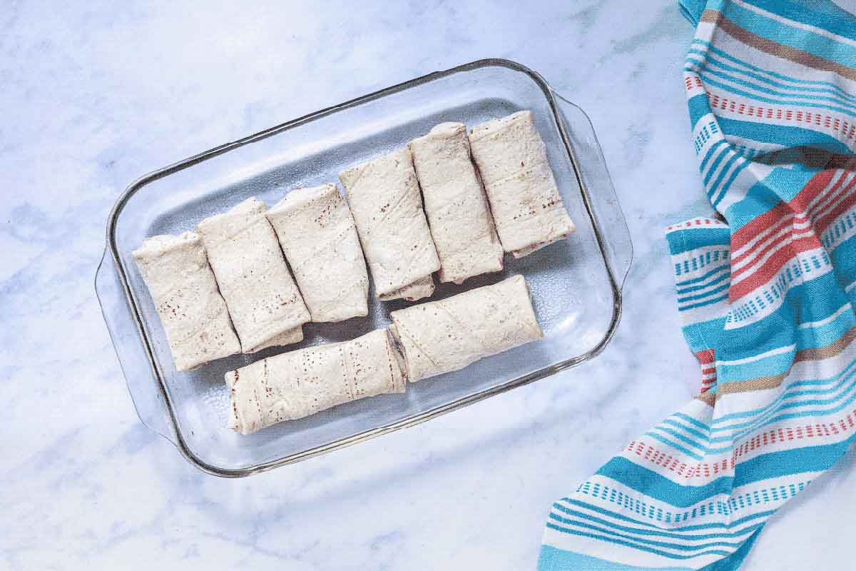 Frozen burritos in a glass baking dish.