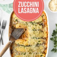 White casserole dish containing zucchini lasagna, with a serving spatula scooping a slice. With text Freezer Friendly Zucchini Lasagna Add Salt & Serve, formerly Menus4Moms