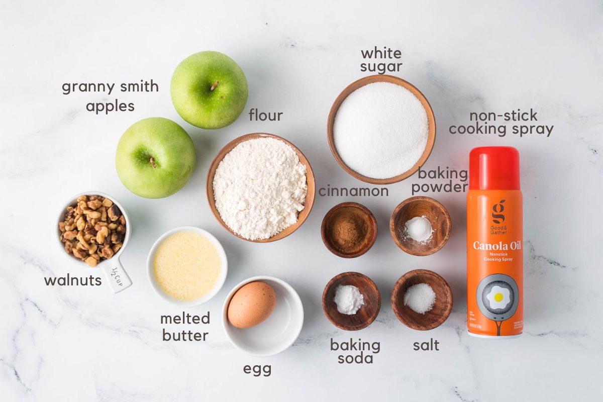 Labeled ingredients for Apple Walnut Bars (two green apples, walnuts, flour, white sugar, melted butter, an egg, ground cinnamon, baking soda, baking powder, salt, and non-stick spray).