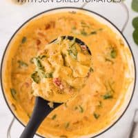 Creamy Tuscan chicken with sun-dried tomatoes, spinach, and mini farfalle in cream sauce in a pot with a serving on a spoon held over the pot and text Creamy Tuscan Chicken with Sun-dried Tomatoes.