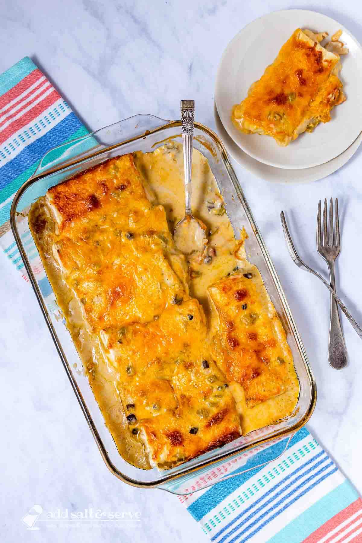 Frozen burrito casserole in a baking dish with a serving on a plate beside it.