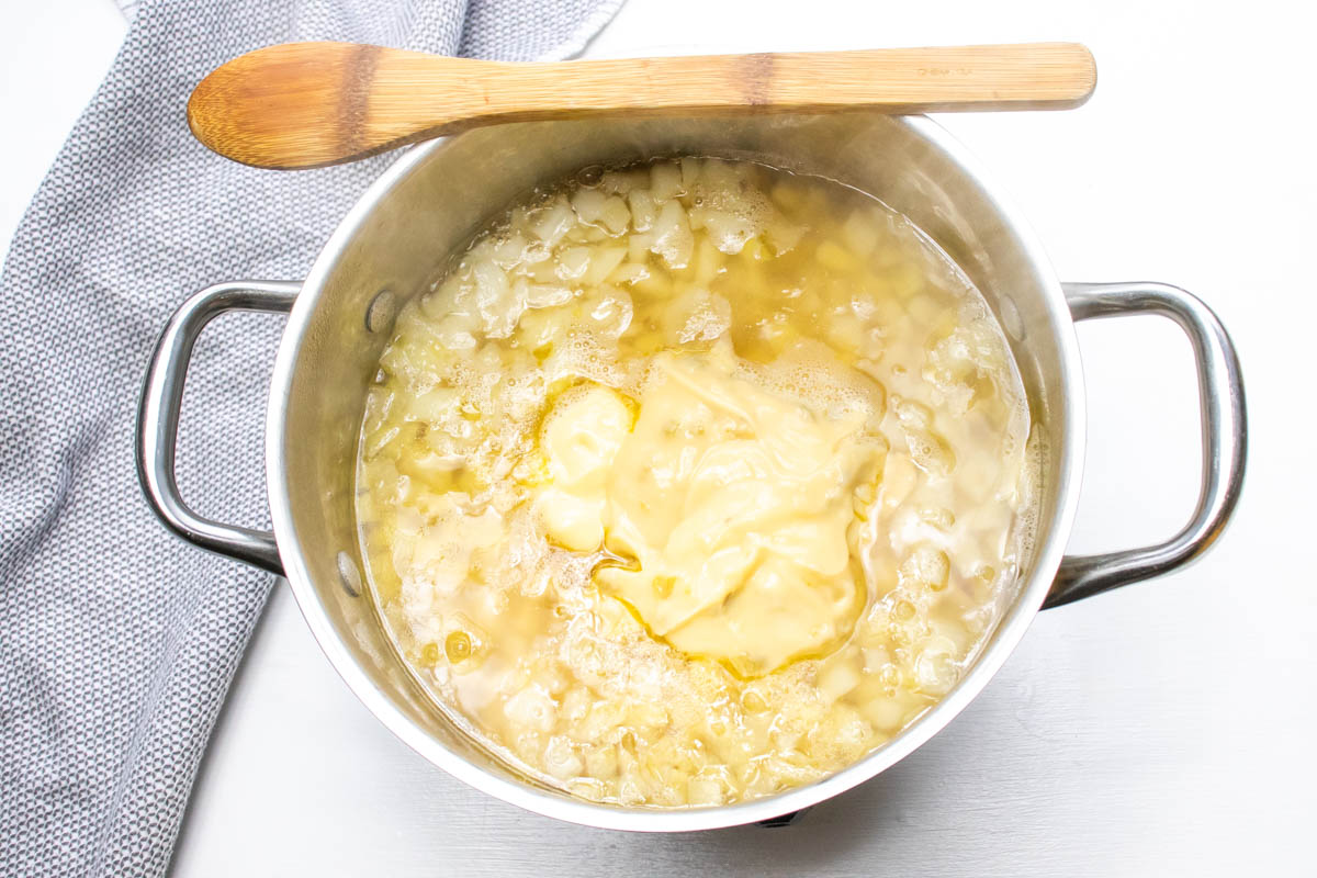 Potato soup after adding cream soups and evaporated milk to the broth, onions, and hash browns.