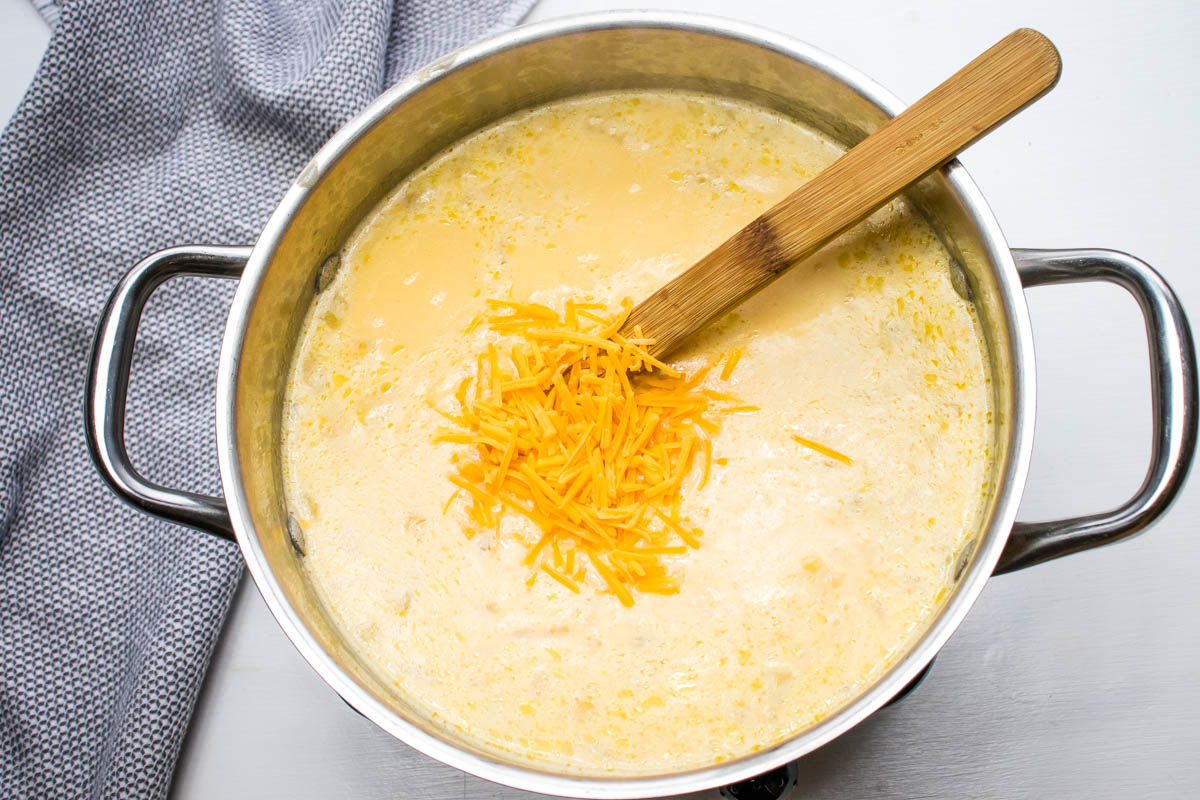 Potato soup with hash browns after simmering and just after adding shredded cheddar cheese.