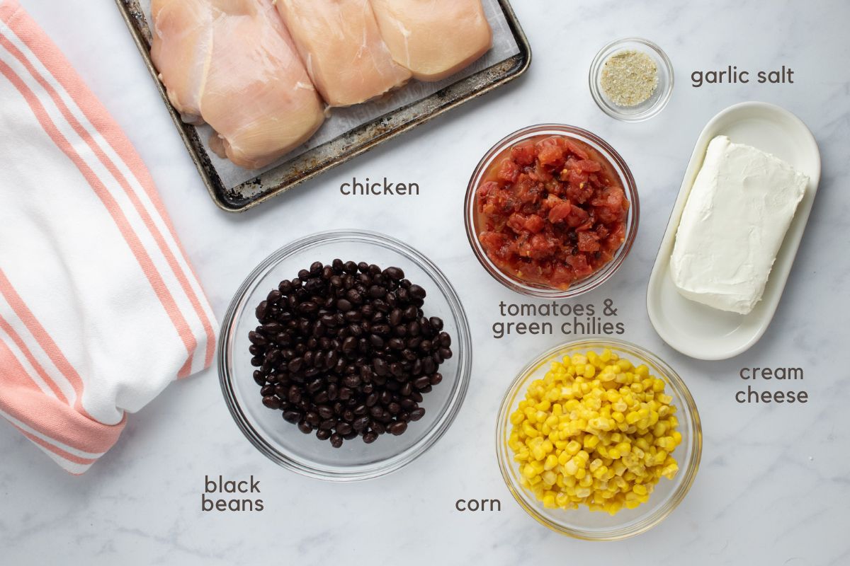 Ingredients for Crockpot Fiesta Chicken: boneless, skinless chicken breasts, black beans, corn kernels, fire-roasted Rotel tomatoes and green chilies, cream cheese, and garlic salt.