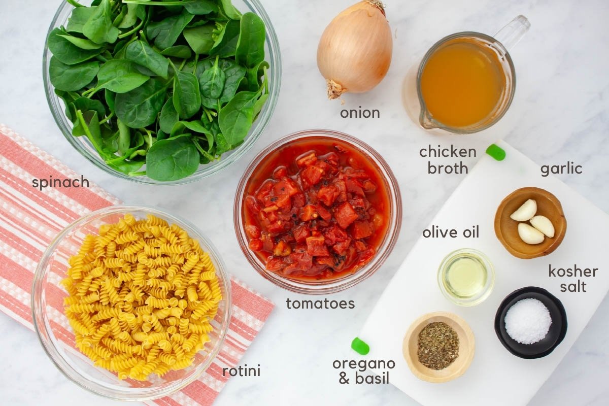 Ingredients for Tomato Basil Pasta (fresh spinach, rotini, diced fire-roasted tomatoes, an onion, chicken broth, garlic cloves, olive oil, basil and oregano, and kosher salt).