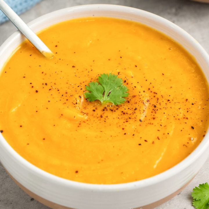 Bowl of butternut squash soup garnished with parsley.