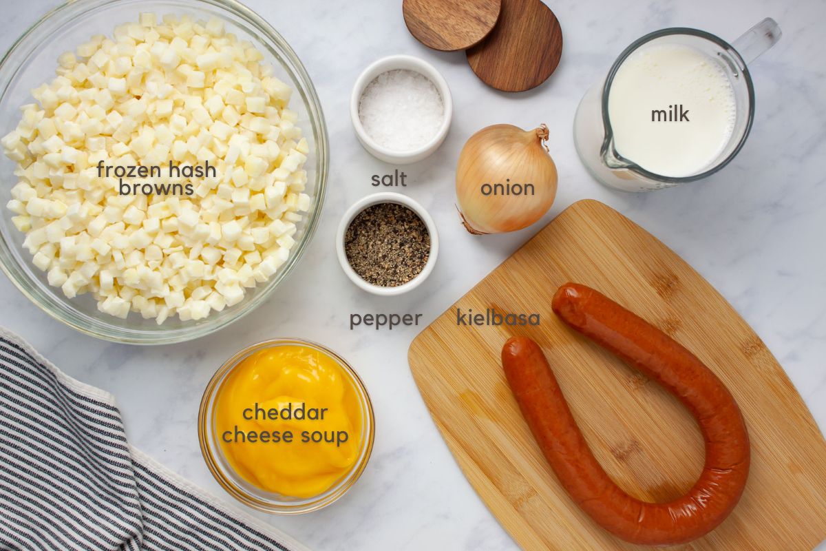 Labeled ingredients for soup: frozen hash browns, condensed cheddar cheese soup, kielbasa, onion, milk, salt and pepper.