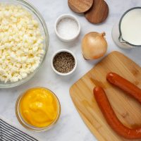 Ingredients for cheesy potato kielbasa soup crockpot: frozen hash browns, condensed cheddar cheese soup, kielbasa, onion, milk, salt and pepper.