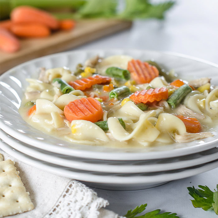 Bowl of chicken noodle soup with carrots, green beans, and corn.