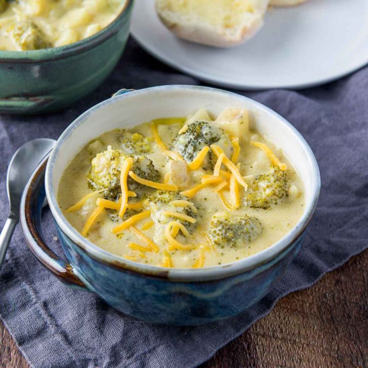 Bowl of cream of broccoli and cheddar soup garnished with cheddar cheese.