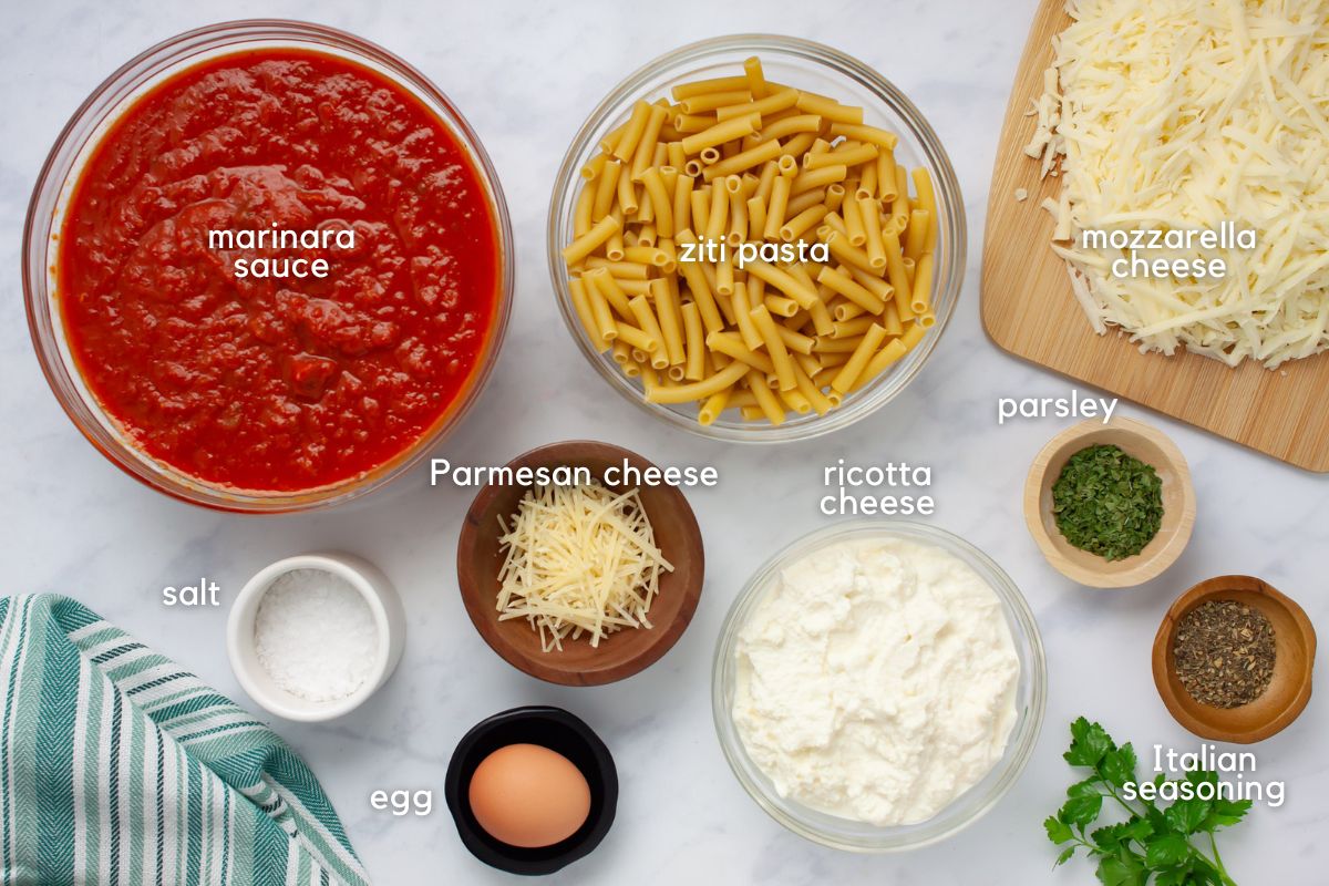 Ingredients for Cheesy meatless Baked Ziti: marinara sauce, ziti pasta, mozzarella cheese, Parmesan cheese, ricotta cheese, parsley, Italian seasoning, an egg, and salt.