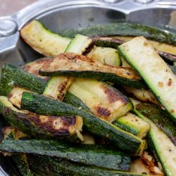 Grilled, sliced zucchini in a pewter serving bowl.